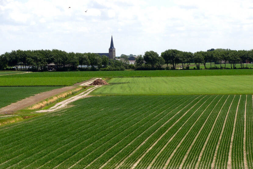 Akkerland bij een dorp met een kerktoren